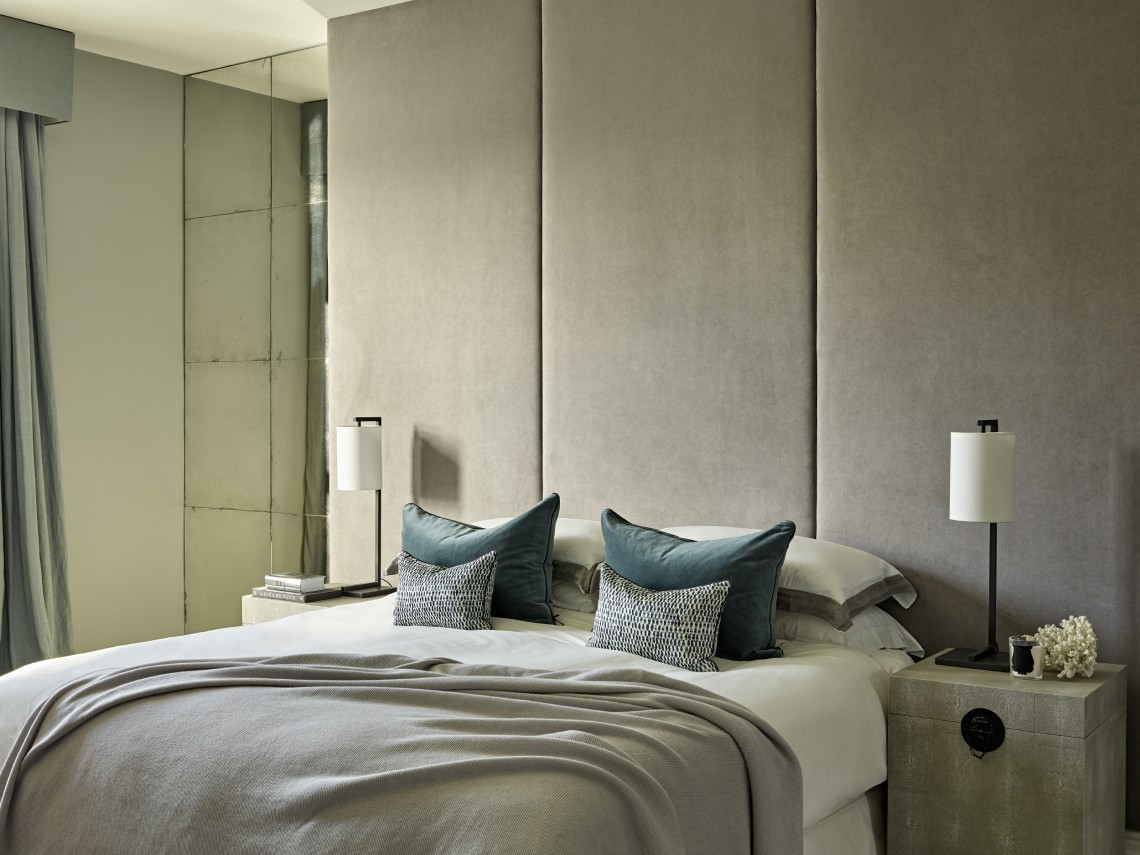 Contemporary London bedroom with upholstered wall panels, layered neutral textiles and refined, modern styling