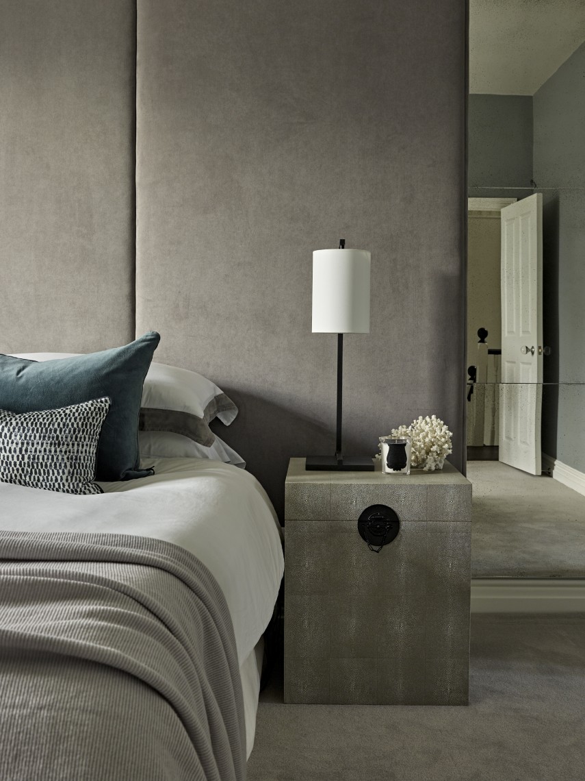 Contemporary London bedroom with bespoke upholstered wall panels, stone bedside table and refined, neutral styling