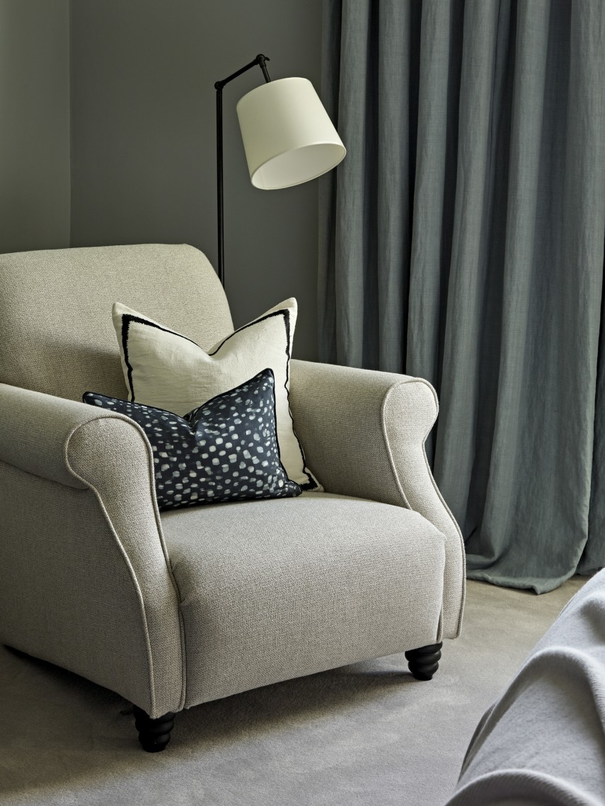 Upholstered armchair and floor lamp in a contemporary London bedroom, styled in soft neutral tones