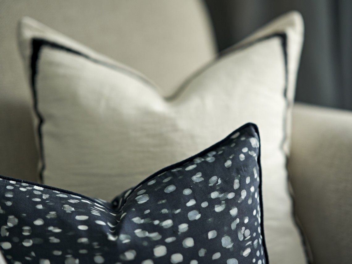 Layered cushions in soft neutral and charcoal tones within a contemporary London interior