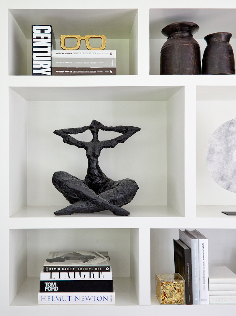 Bespoke white joinery shelving in the living room, styled with curated art objects, books and sculptural accessories.
