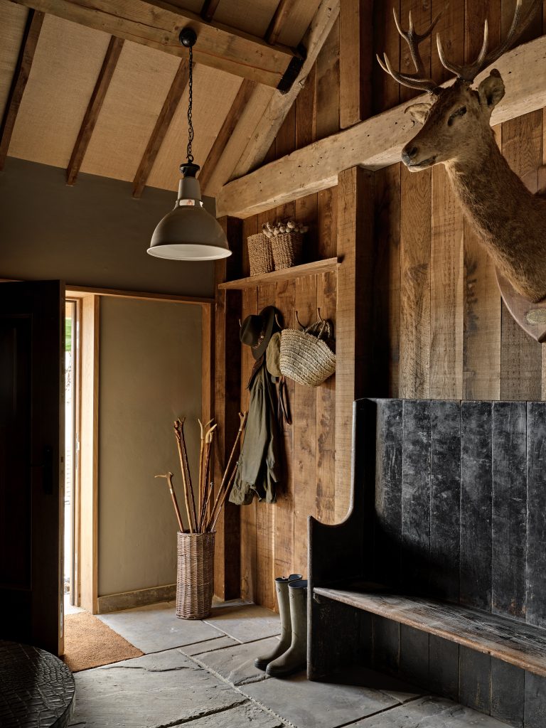 Rustic boot room in a Cotswolds country house with exposed timber beams, bespoke joinery and natural stone flooring.